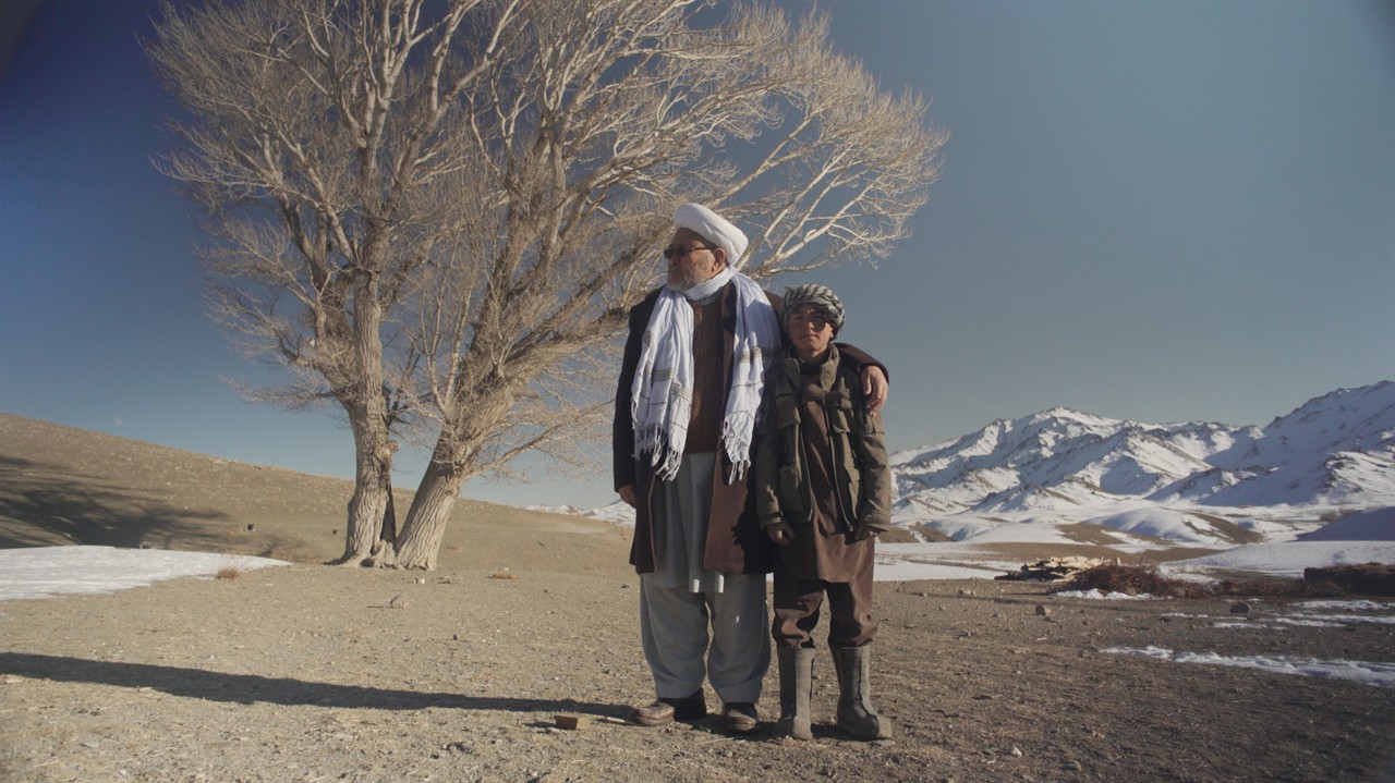 A man stands with his arm around a boy